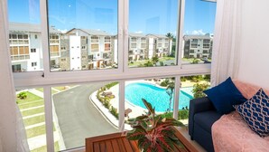 A room with a large window overlooking a swimming pool and a residential area.