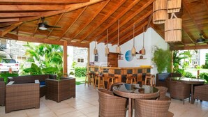 An outdoor patio area with wicker furniture, a bar, and hanging light fixtures.