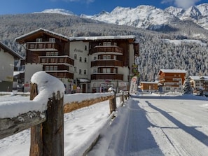 A snow-covered mountain town with a multi-story hotel named 'Evita' and a ski resort sign.