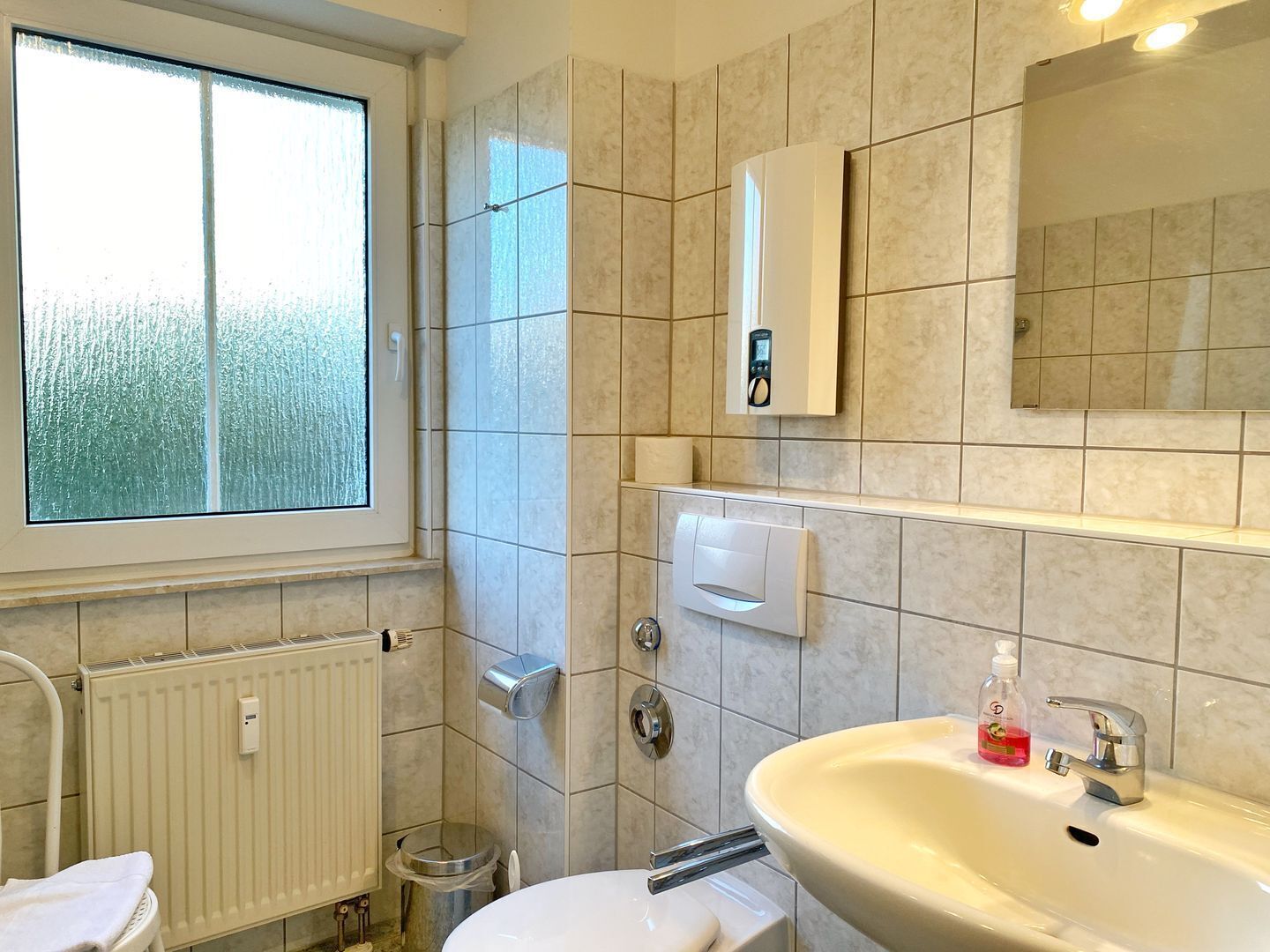 Een moderne badkamer met toilet, wastafel en douche.