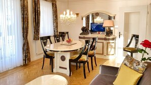 Un coin repas avec une table ronde, des chaises, un lustre et un téléviseur en arrière-plan.