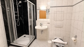 Un baño moderno con ducha de vidrio, lavamanos, inodoro y espejo.