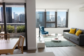 Relax in a stylish space with a city view, featuring a sofa, armchair, and dining table.