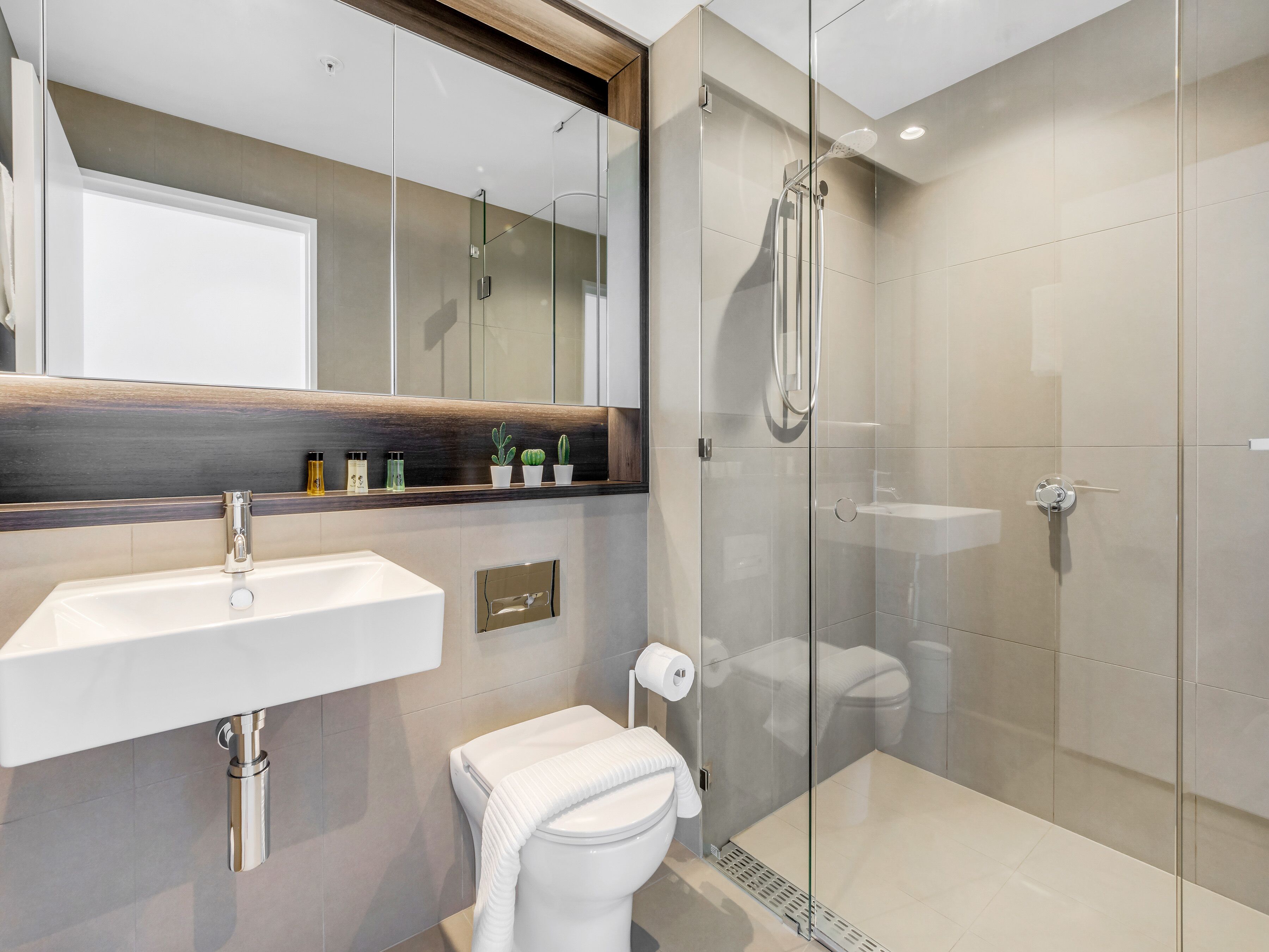 A modern bathroom with a glass-enclosed shower, a white sink, and a toilet.