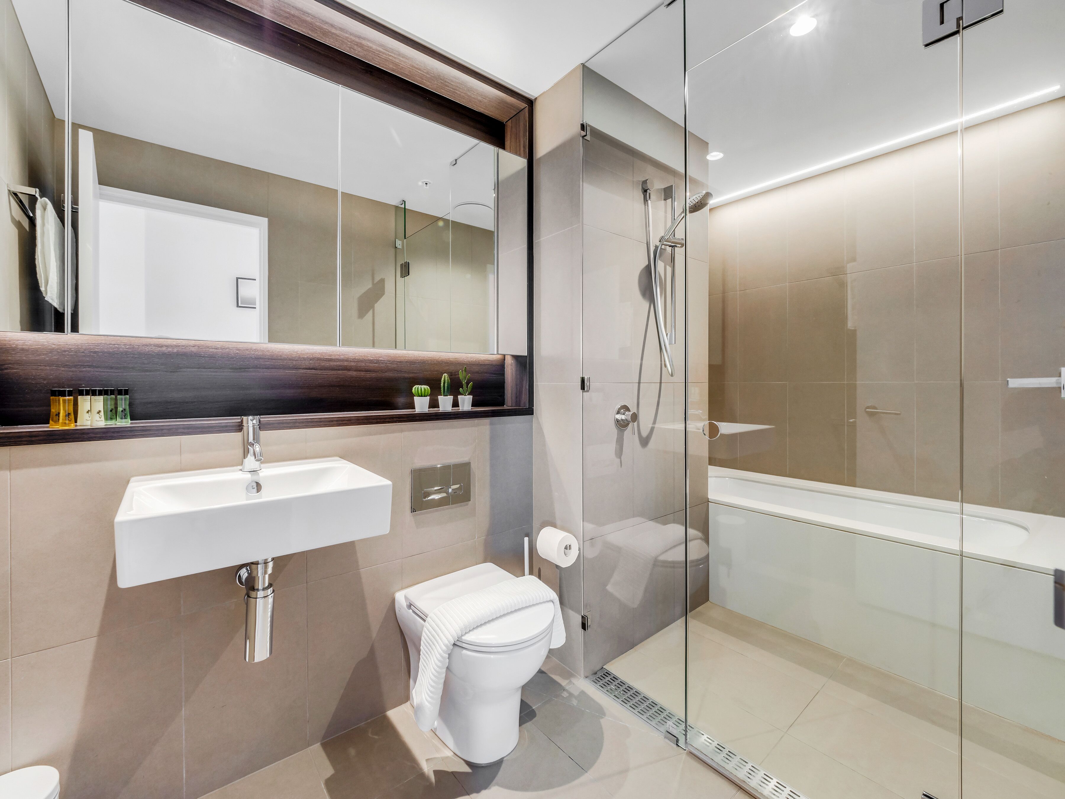 A modern bathroom with a glass-enclosed shower, a white sink, and a toilet.