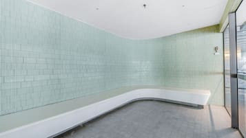 Bathroom features a curved bench, large window, and recessed lighting.