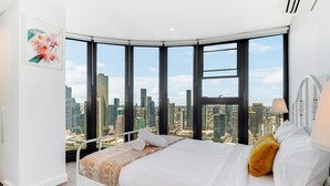 A bedroom with a city view, a bed, a nightstand, and a window with blinds.
