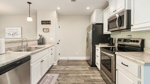 A modern kitchen with white cabinetry, stainless steel appliances, and a granite countertop.