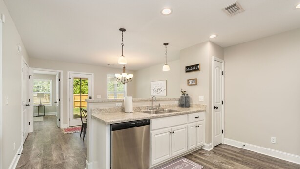 A kitchen with white cabinets, a stainless steel dishwasher, and a granite countertop.