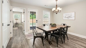 A dining area with a wooden table and black chairs, a chandelier, and a sign on the wall.
