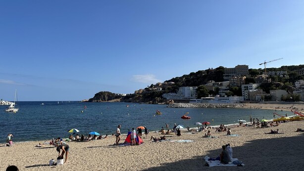 A beach with people, tents, and boats.