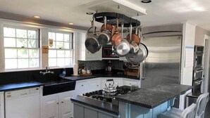 A modern kitchen with white cabinets, a black countertop, and a stainless steel refrigerator. - Historic, Antique Southern Maine Farmhouse For All Seasons - 5 mins to Portland! (Falmouth)