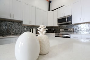 Una cocina con gabinetes blancos, un microondas y dos jarrones decorativos sobre la encimera.