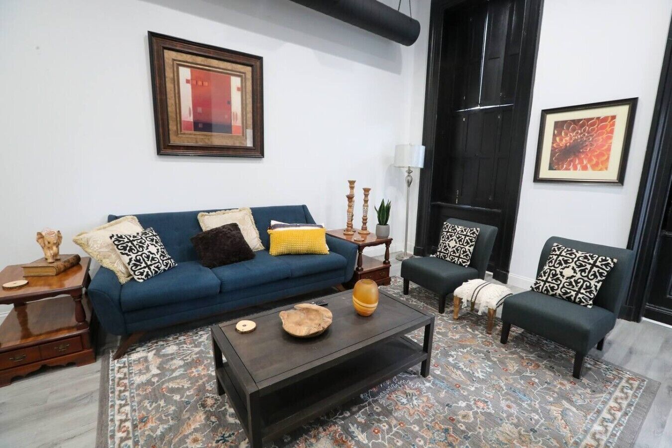 A living room with a blue sofa, a black armchair, a coffee table, and a patterned rug.