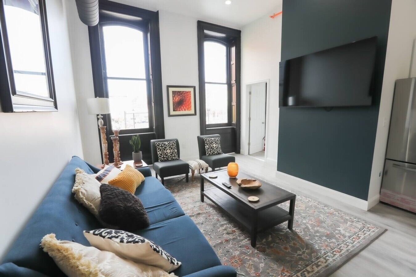 Ein modernes Wohnzimmer mit einer Couch, Sesseln, einem Couchtisch und einem Fernseher.