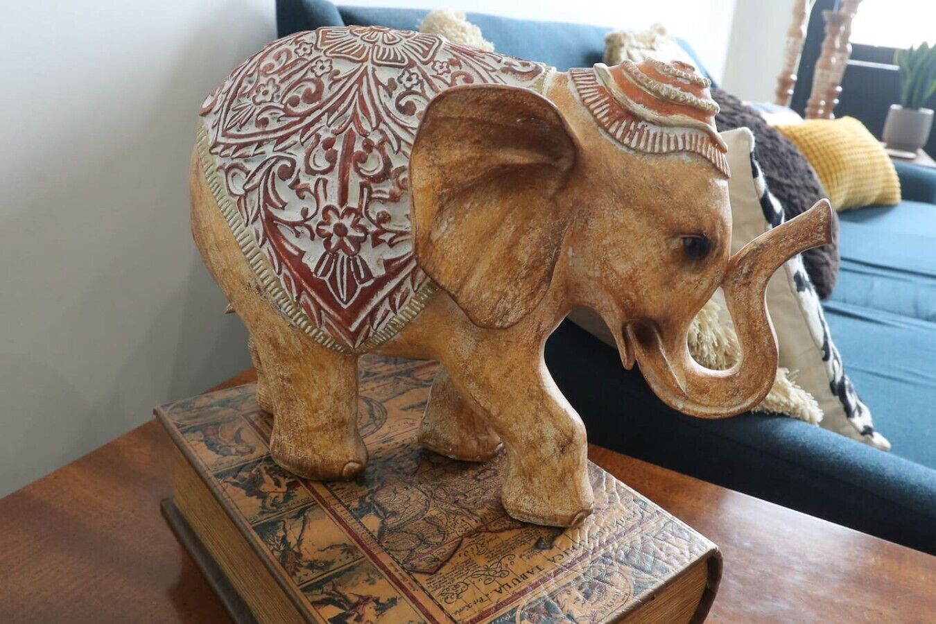 A wooden elephant sculpture on a book with a patterned cover.