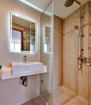 A modern bathroom with a glass-enclosed shower, a large mirror, and a sink with a chrome faucet.