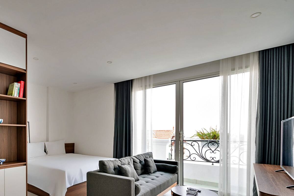 Una habitación de hotel con cama, sofá, una mesita y balcón con vistas.