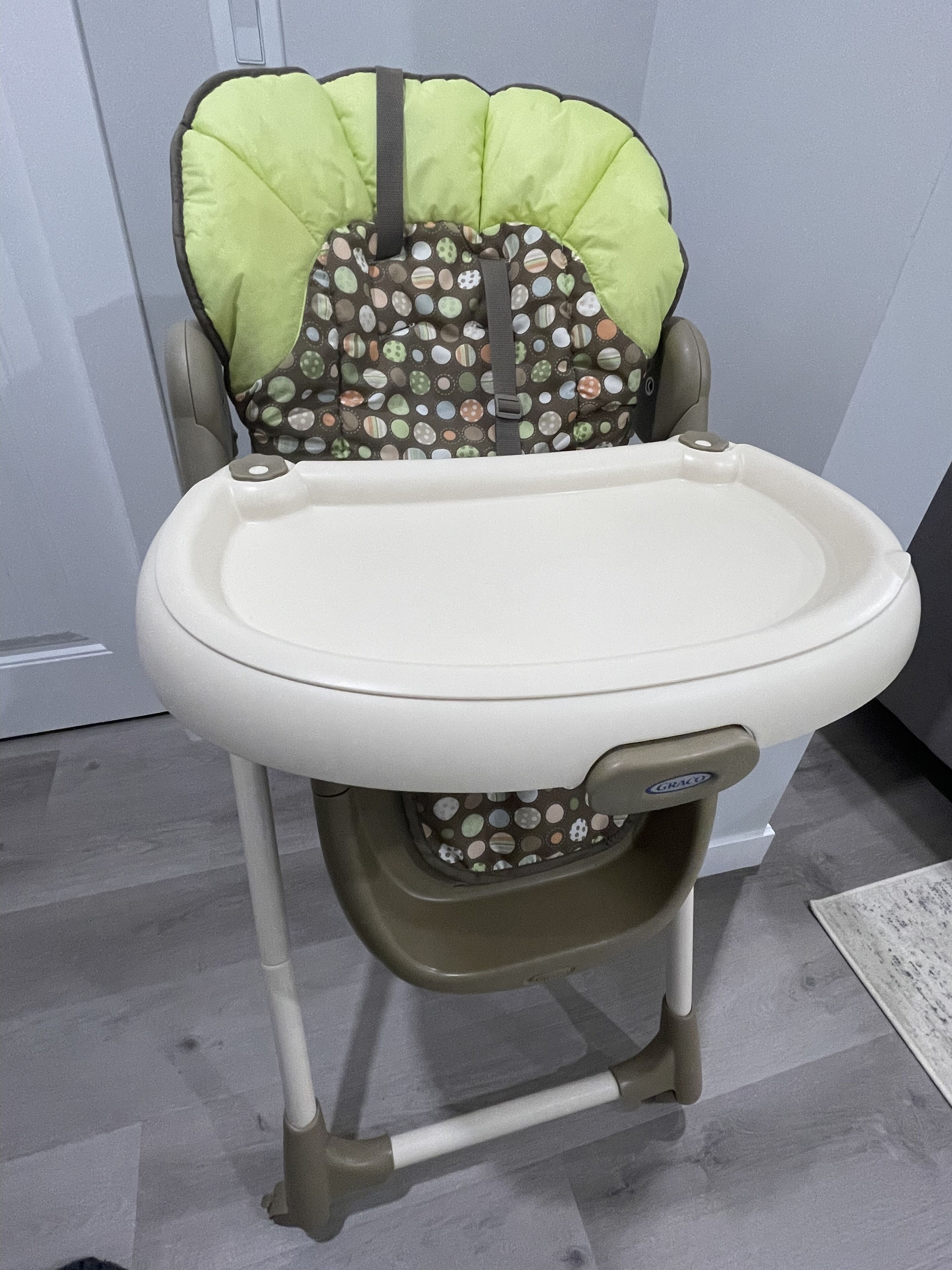 Une chaise haute avec un coussin vert et un siège à motifs.