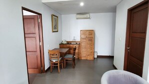 A hallway with a dining area, a sofa, and a wooden cabinet. - Nelayan Sanur Bay (Bali)