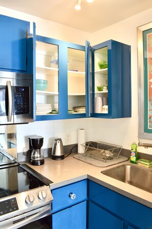 A kitchen with blue cabinets, a stainless steel microwave, a coffee maker, and a sink. - Cozy Condo 5 minutes from strip, airport, and UNLV (Las Vegas)