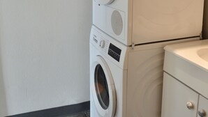 Un appareil combiné lave-linge et sèche-linge, avec les bouteilles de lessive posées sur le dessus.