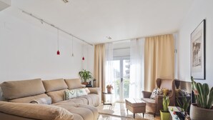 A modern living room with a beige sofa, a coffee table, and a small side table with plants.