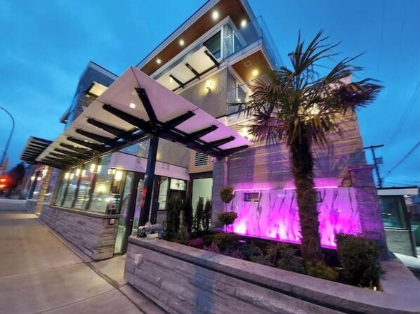 A modern building with a covered entrance and a water feature illuminated by purple lights.