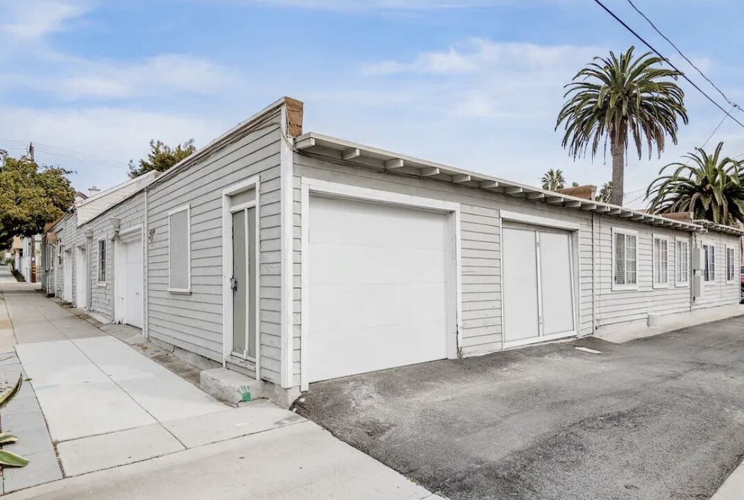 A single-story building with a garage door, a small porch, and a clear sky.