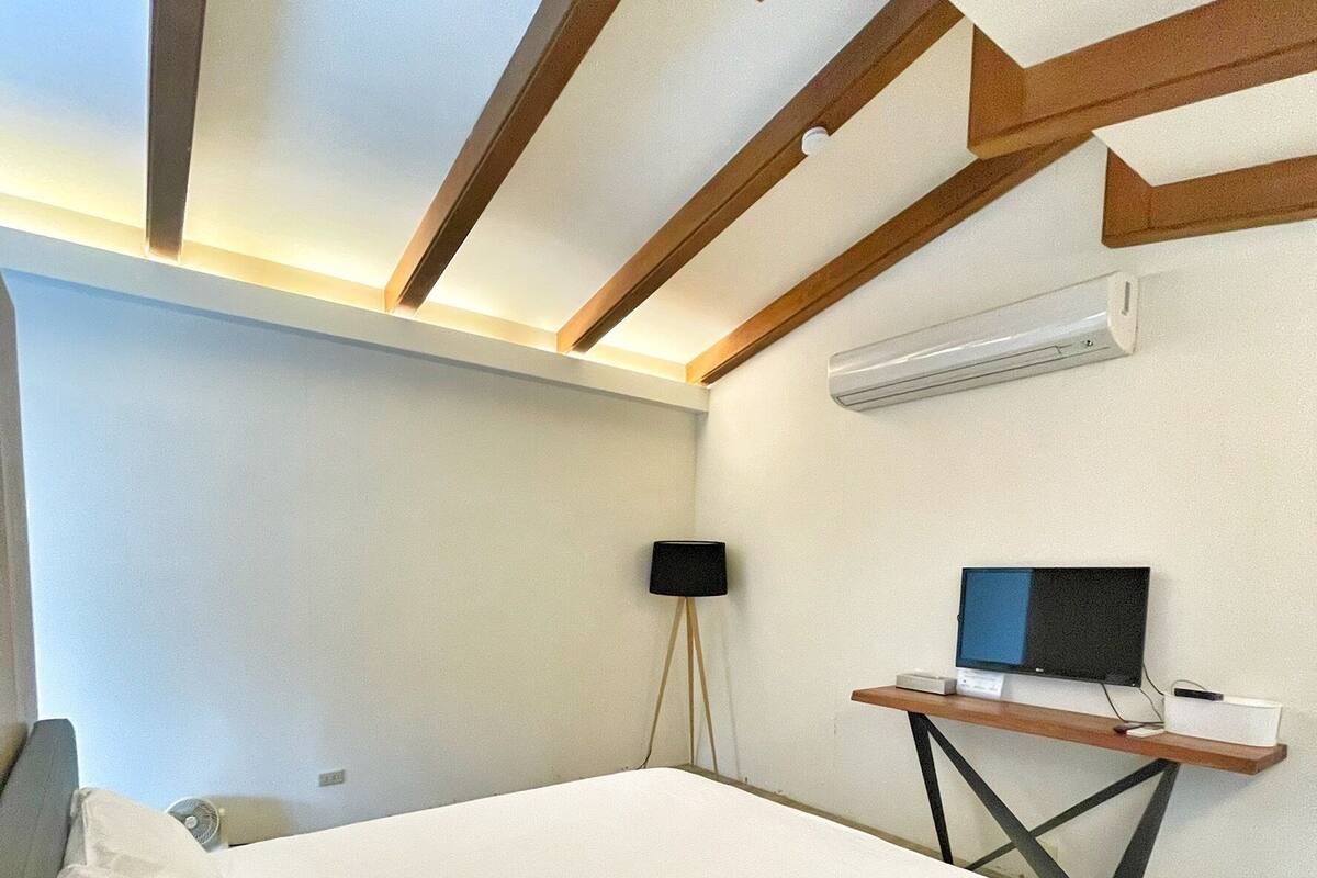 Una camera da letto con un letto, una scrivania con un computer e un condizionatore d'aria a parete.
