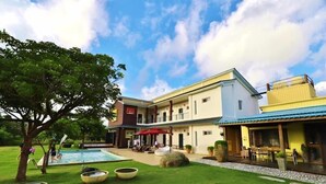 A hotel with a swimming pool, outdoor seating, and a well-maintained lawn. - Kenting Grandmas (Hengchun)