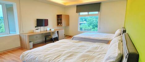 Une chambre moderne avec deux lits, un bureau, une télévision et une fenêtre donnant sur un paysage verdoyant.