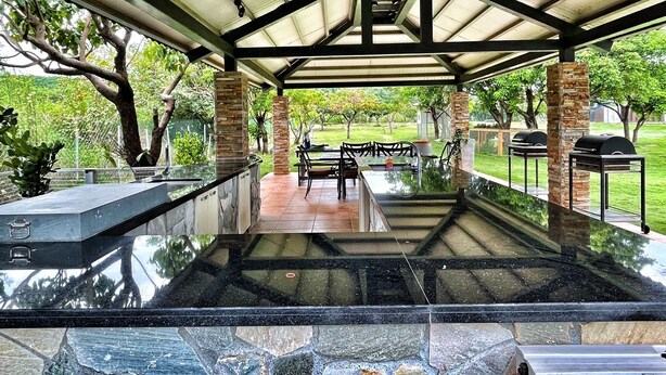 An outdoor covered patio with a glass-top table, chairs, and a grill area. - Kenting Grandmas (Hengchun)