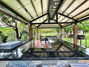 An outdoor covered patio with a glass-top table, chairs, and a grill area. - Kenting Grandmas (Hengchun)