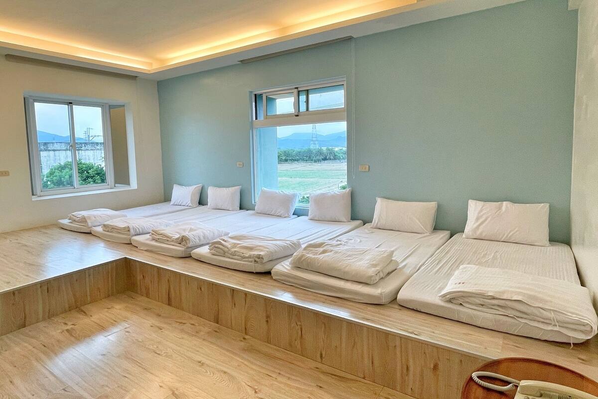 Una camera d'albergo con un letto grande, un letto più piccolo e una scrivania con il telefono.
