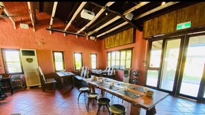A restaurant with a long communal table, bar stools, and a tiled floor. - Kenting Grandmas (Hengchun)
