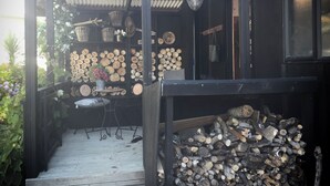 Un'area esterna riparata con una panca in legno, un tavolo con un cesto e un lampadario.