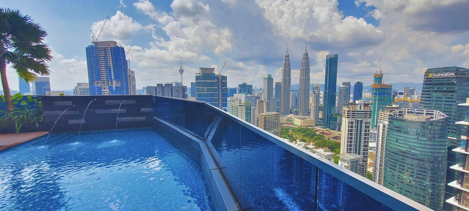 Una piscina en la azotea con vistas a un paisaje urbano, incluyendo edificios altos y un cielo despejado.