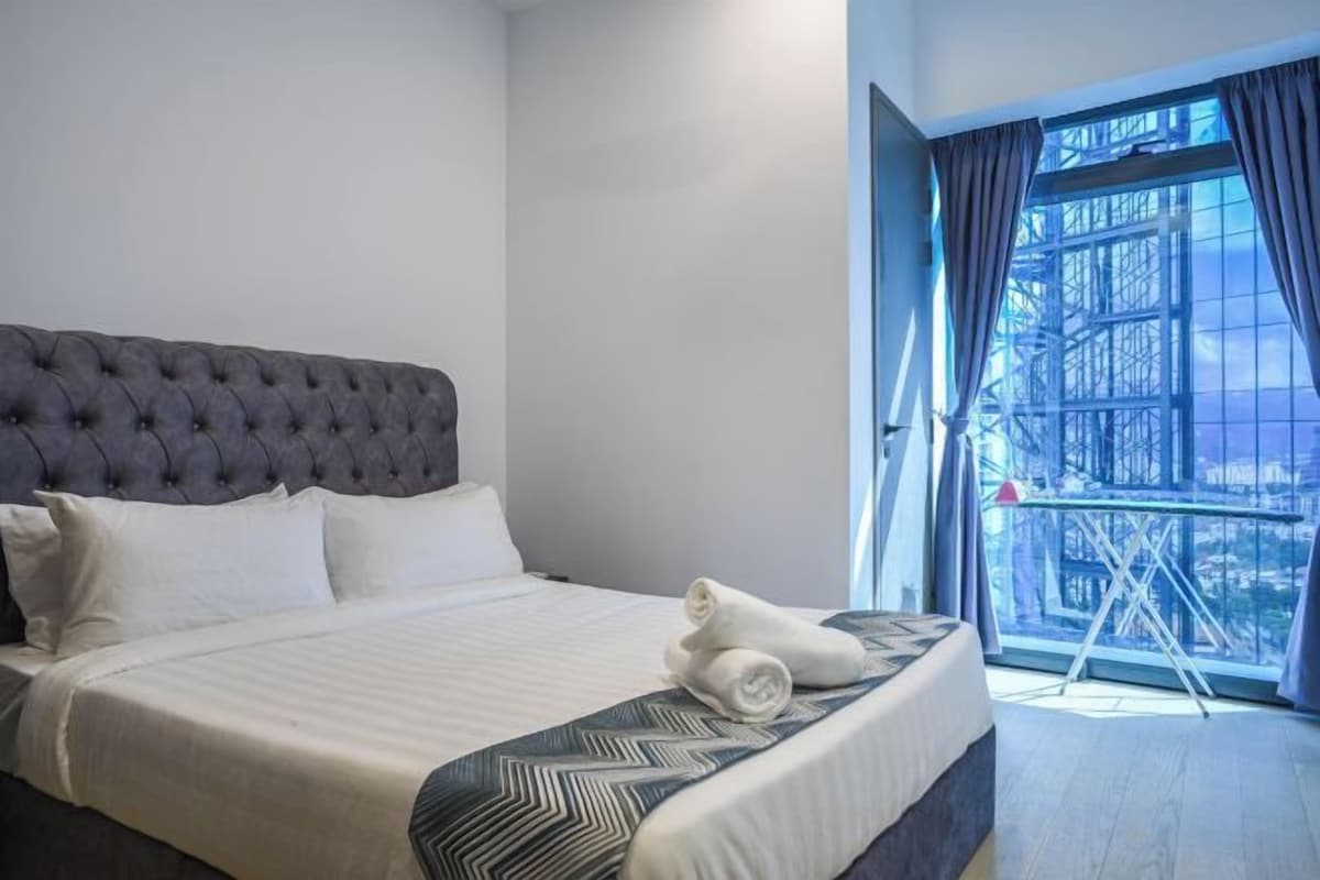 A hotel room with a large bed, a window with curtains, and a view of the outside.