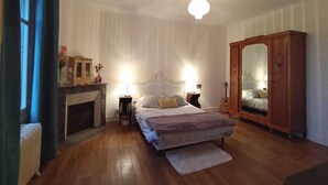 Un dormitorio con cama, armario, mesita de noche, lámpara y chimenea.