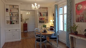 Un comedor con mesa y sillas de madera, rodeado de estanterías llenas de libros y objetos decorativos.