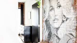 A room with a brick wall mural, a black cabinet, and a plant hanging from the ceiling.