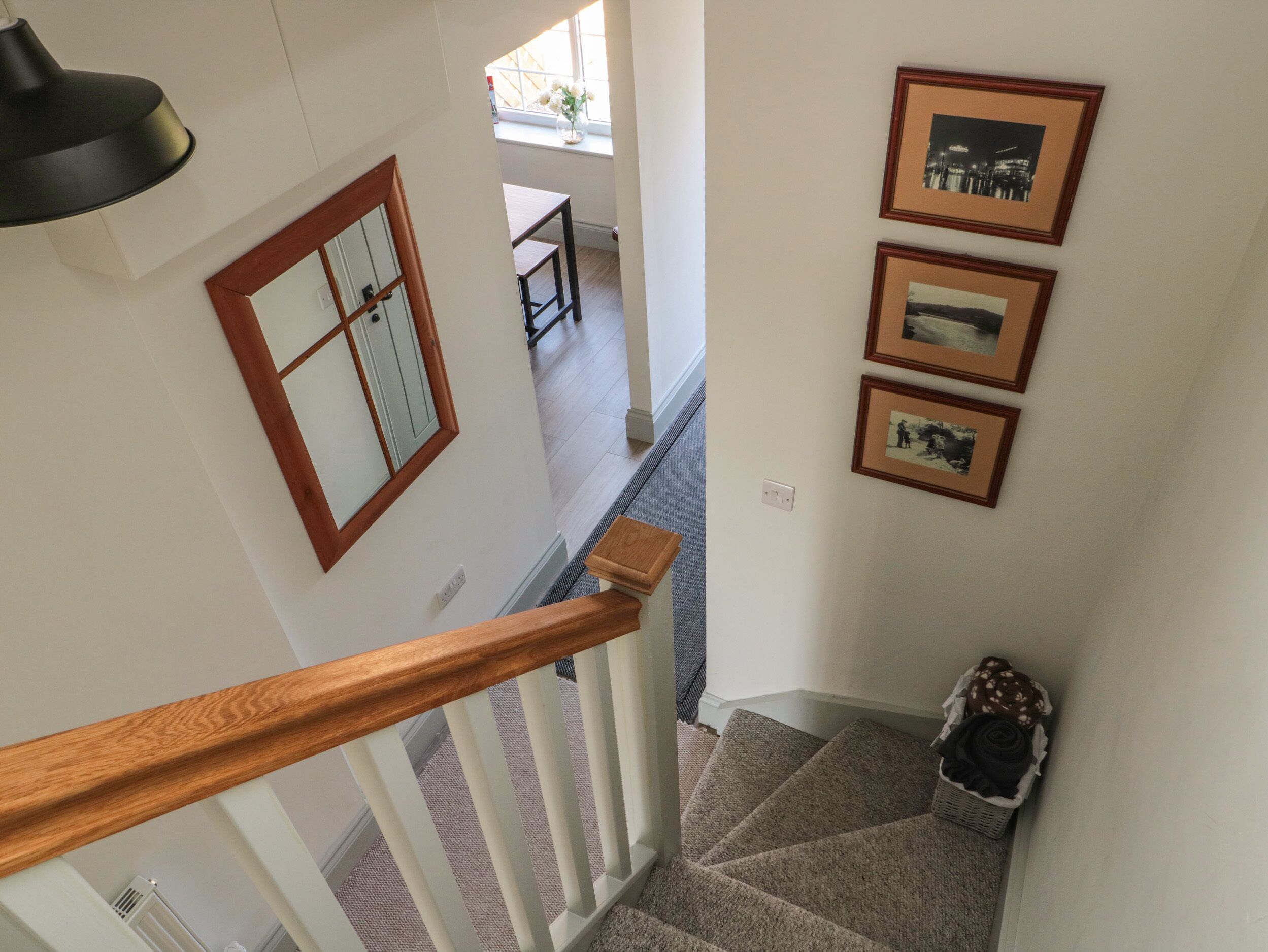 Eine Treppe mit Holzwandhandlauf, einem an der Wand befestigten Bilderrahmen und einem Korb voller Gegenstände auf der Landung.