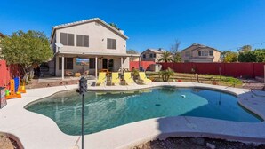 A residential property with a swimming pool, a covered patio, and a two-story house.