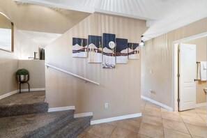 A staircase with a handrail, a wall-mounted artwork, and a door leading to another room.