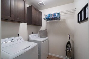A laundry room with a washing machine, dryer, and a vacuum cleaner.