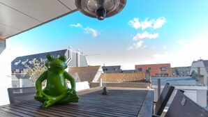 A rooftop terrace with a green frog sculpture, a table, and chairs. - Lilly with parking by Interhome (Bredene)