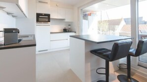 A modern kitchen with white cabinets, a built-in oven, and a large window offering a view of the city. - Lilly with parking by Interhome (Bredene)