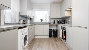 Eine moderne Küche mit weißen Schränken, einer integrierten Waschmaschine, einer Mikrowelle und einem Backofen.