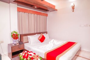 A hotel room with a bed, a nightstand, a telephone, a vase of flowers, and a wall-mounted light fixture. - Hotel Air Inn (Dhaka)